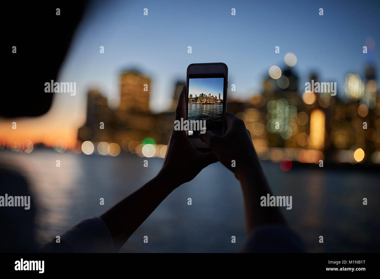 Silhouette di turistica prendendo foto della Skyline di Manhattan al crepuscolo Foto Stock