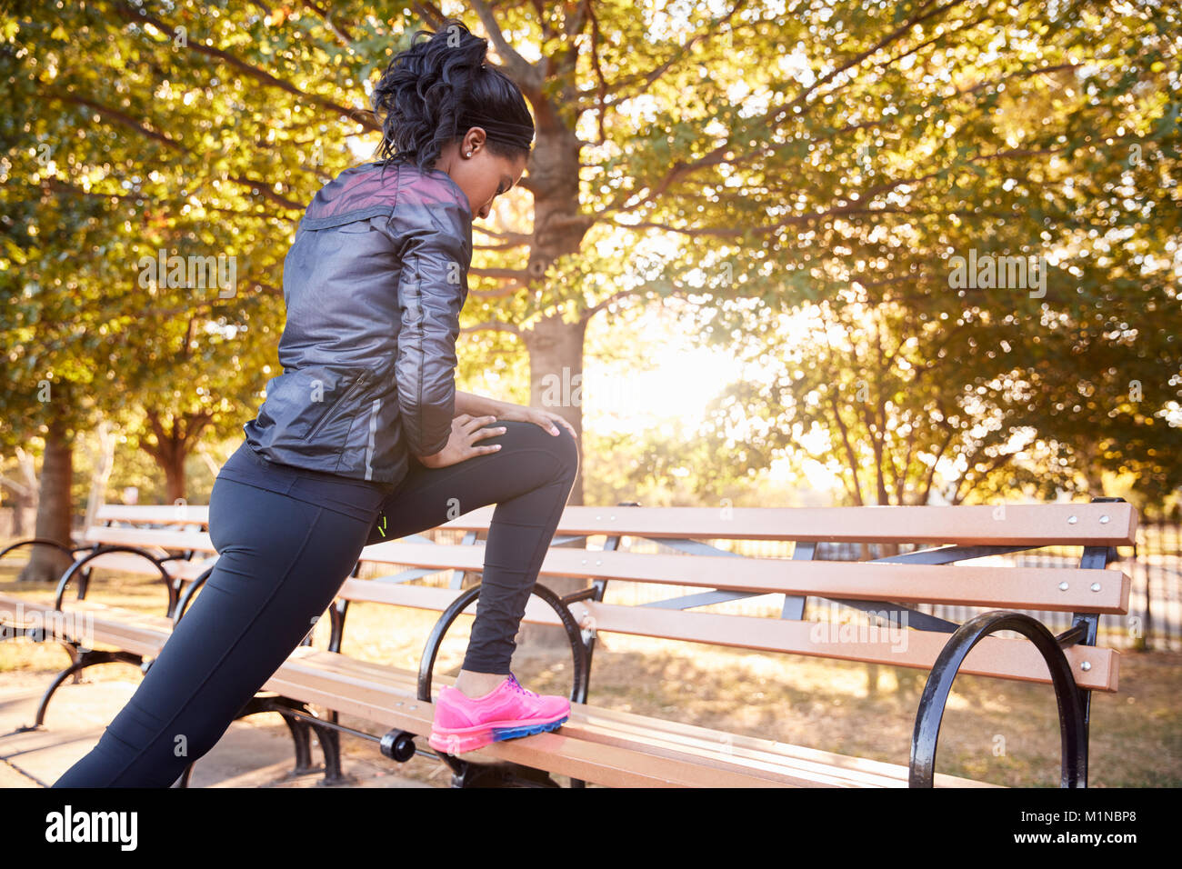 Giovane donna nera stretching su una panchina in un parco di Brooklyn Foto Stock