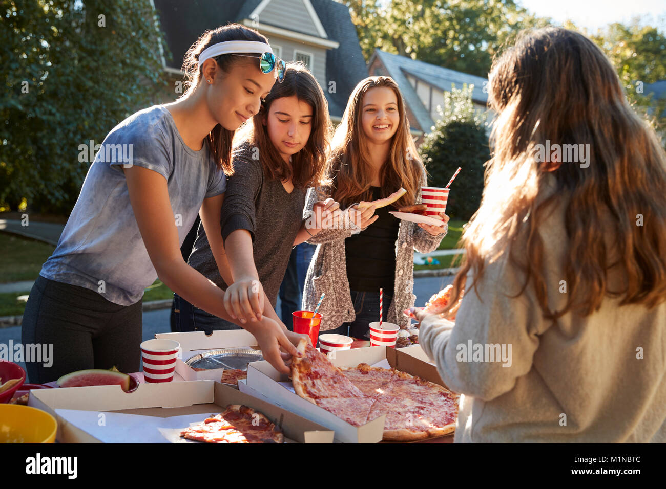 Le ragazze adolescenti la condivisione di una pizza a un quartiere block party Foto Stock