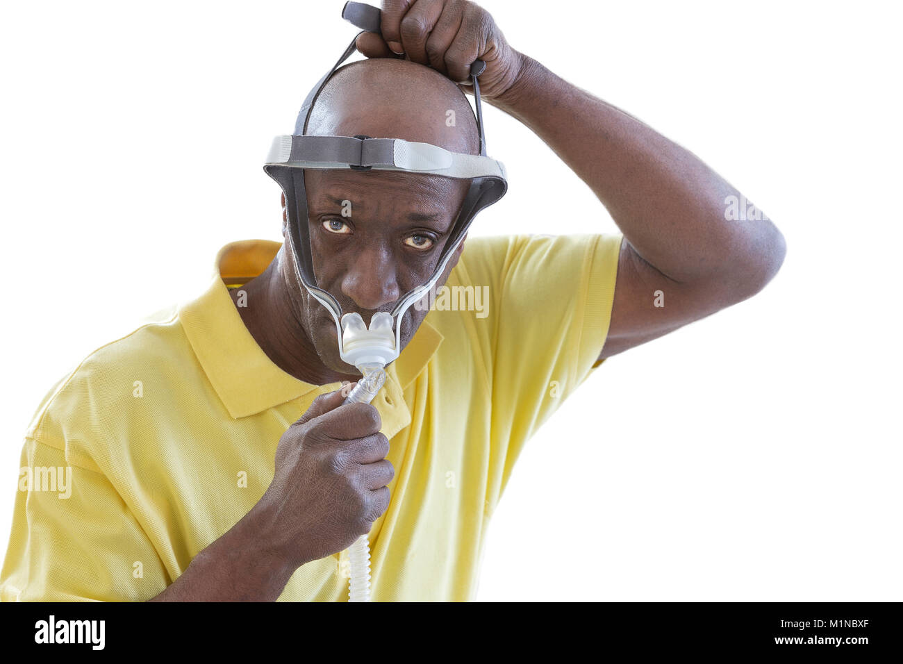 Uomo con un disturbo del sonno cerca su una Cpap per la prima volta,l uomo impara a regolare la sua apparecchiatura CPAP su sfondo bianco Foto Stock