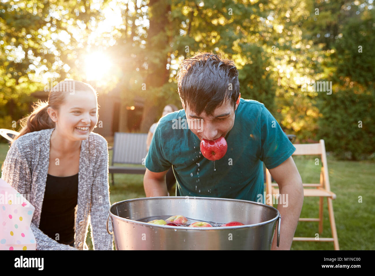 Ragazzo adolescente, Apple in bocca, apple bobbing al party in giardino Foto Stock
