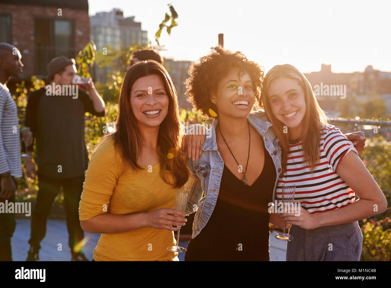 Amici di sesso femminile a una festa sul tetto di sorridere alla telecamera Foto Stock