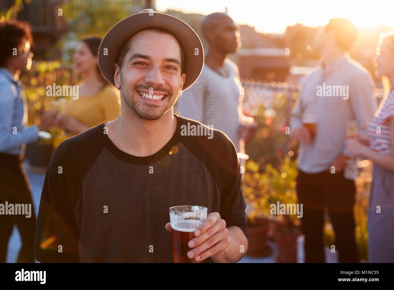 Giovane uomo a una festa sul tetto di sorridere alla telecamera Foto Stock