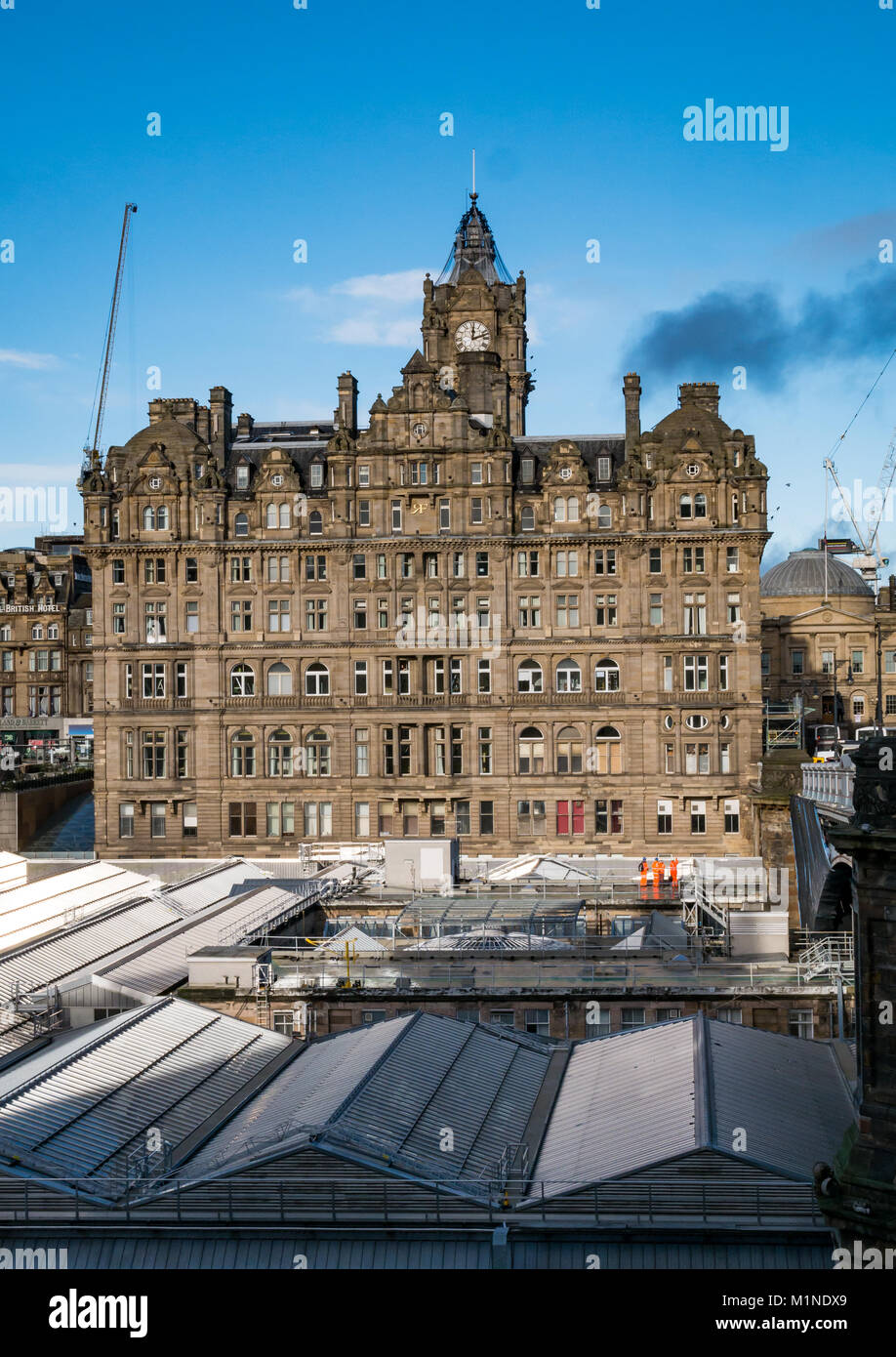 Rocco Forte Balmoral Hotel, Princes Street, Edinburgh, Regno Unito, con la stazione di Waverley tetto nella parte anteriore e cielo blu, gru a distanza Foto Stock
