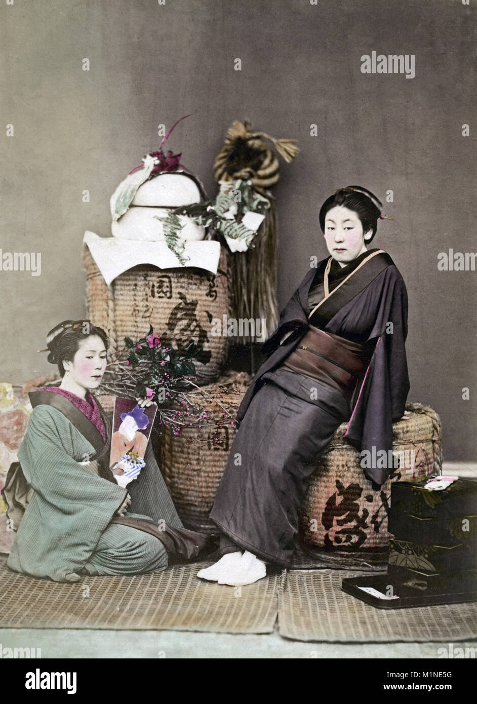 Due geishe con fiori e cesti in una impostazione di studio Foto Stock