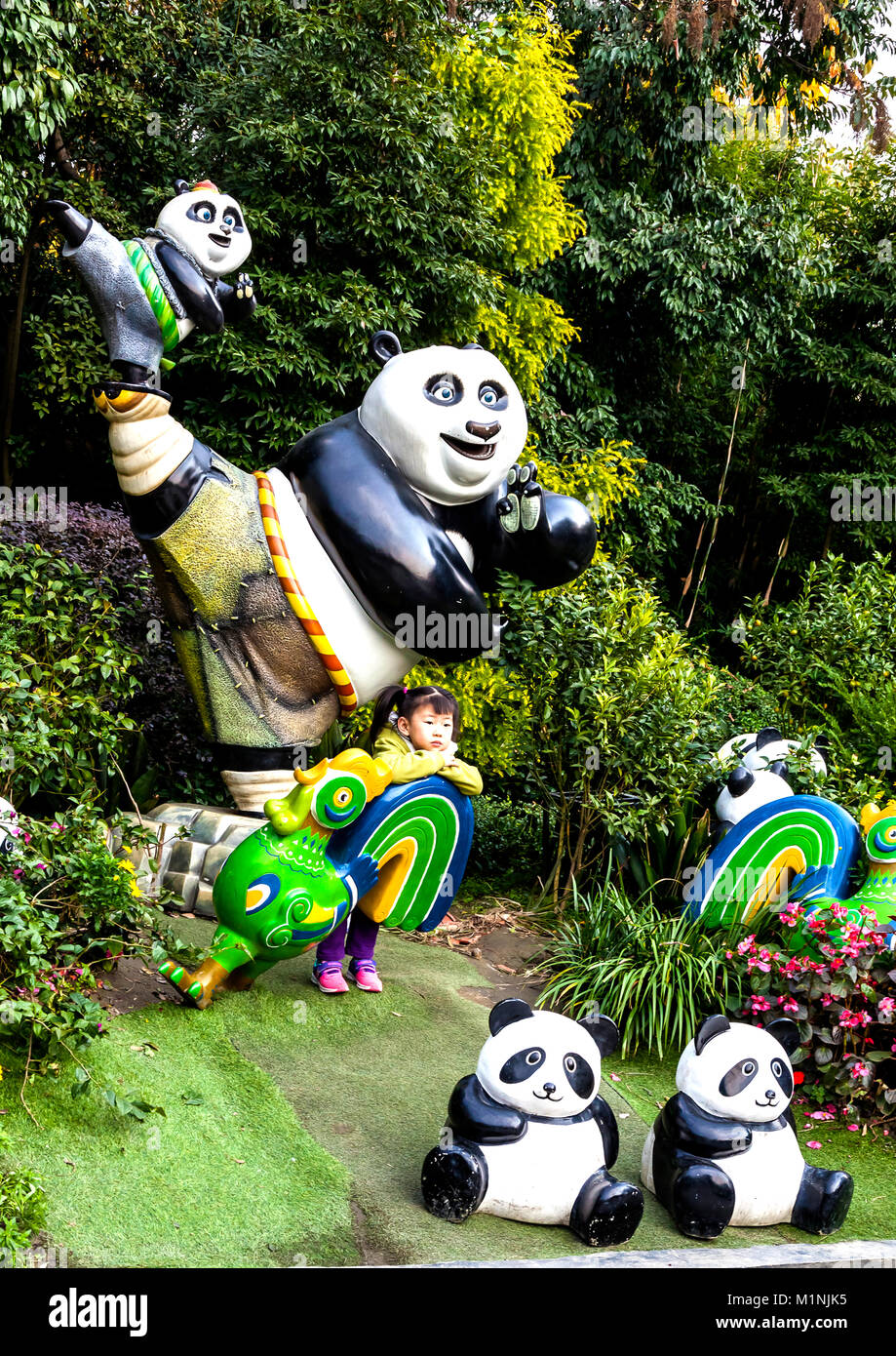 Ragazzo cinese che pongono tra i panda modello a Chengdu Research Base del Panda Gigante di allevamento in Cina Foto Stock