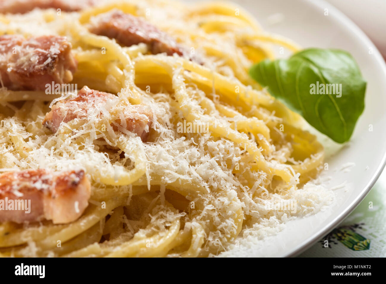 La piastra con i tradizionali piatti di pasta italiana Carbonara con parmigiano e basilico Foto Stock