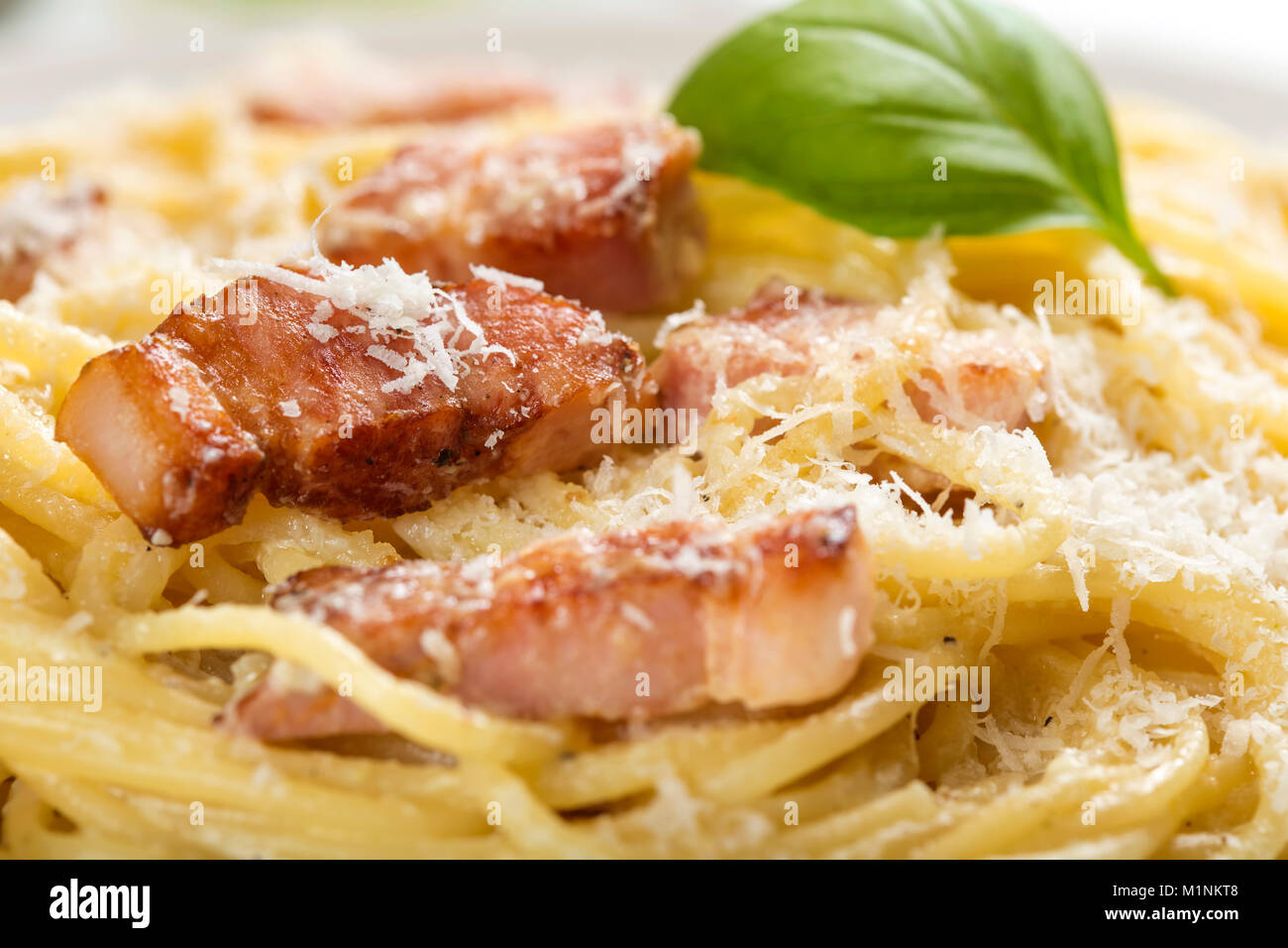 La piastra con i tradizionali piatti di pasta italiana Carbonara con parmigiano e basilico Foto Stock