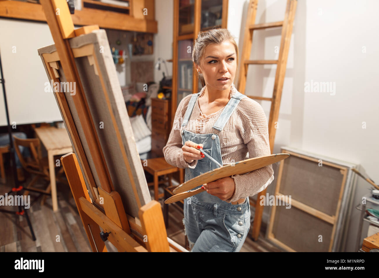 Ragazza sorridente pitture su tela con colori ad olio in laboratorio Foto Stock