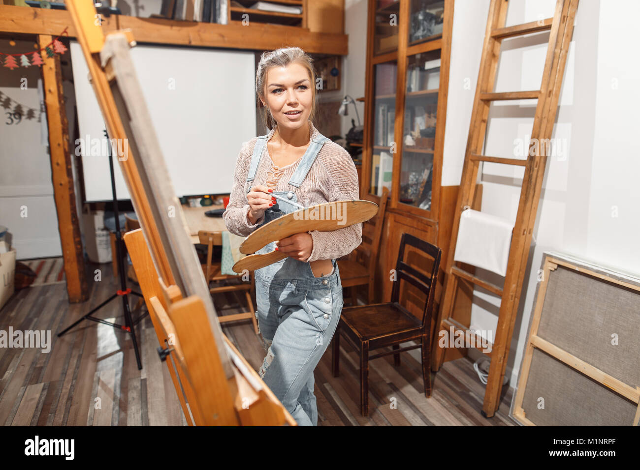 Ragazza sorridente pitture su tela con colori ad olio in laboratorio Foto Stock