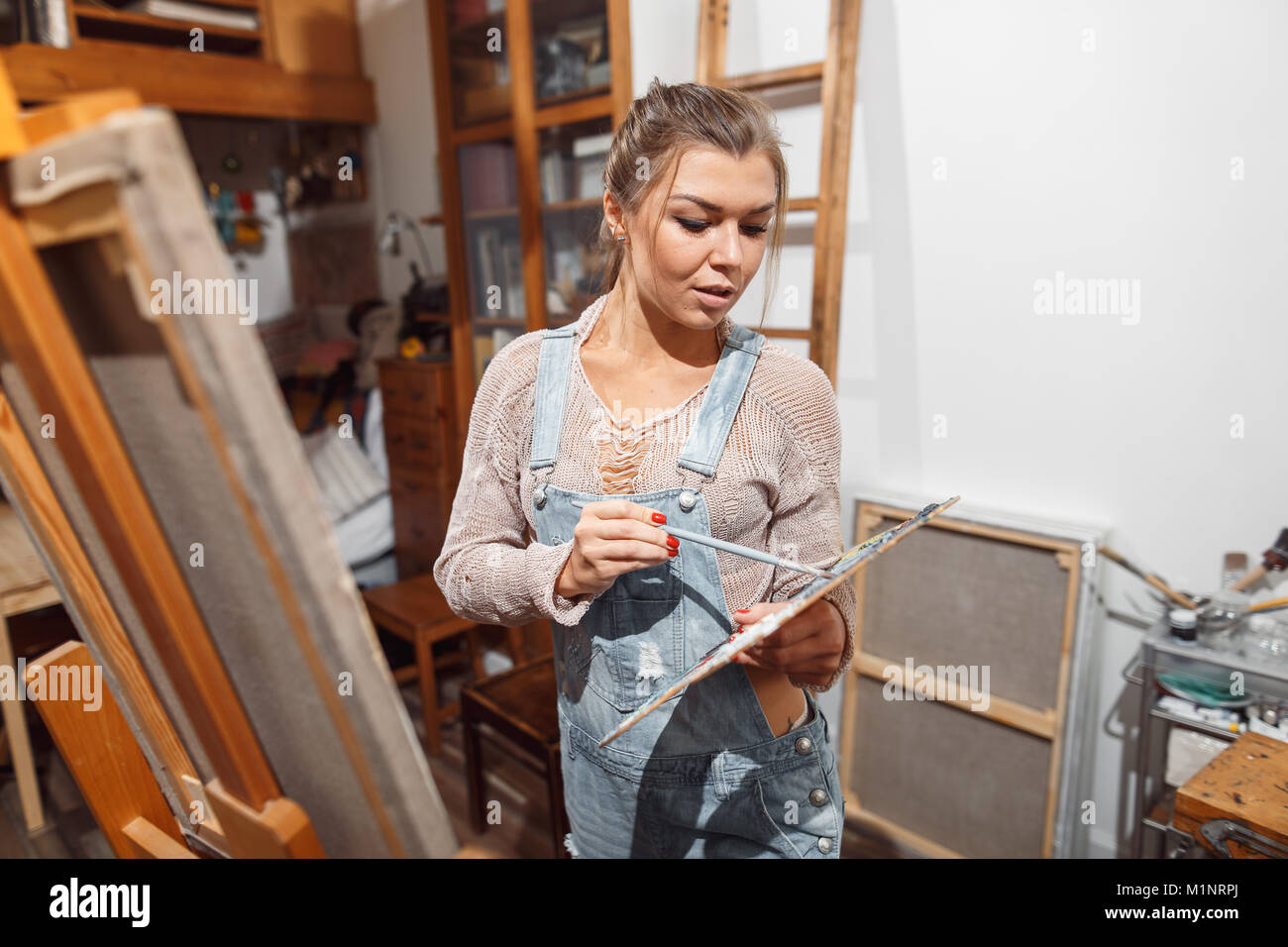 Ragazza sorridente pitture su tela con colori ad olio in laboratorio Foto Stock