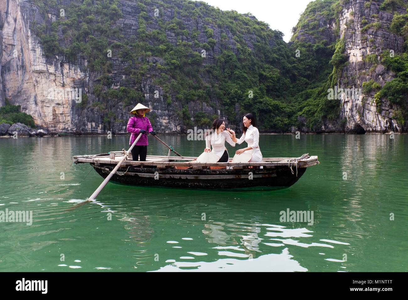Giovani donne touring su una barca a remi (sampan) nella baia di Halong, Vietnam. Le isolette di calcare e di formazioni rocciose sono diventati un'UNESCO area protetta. Foto Stock