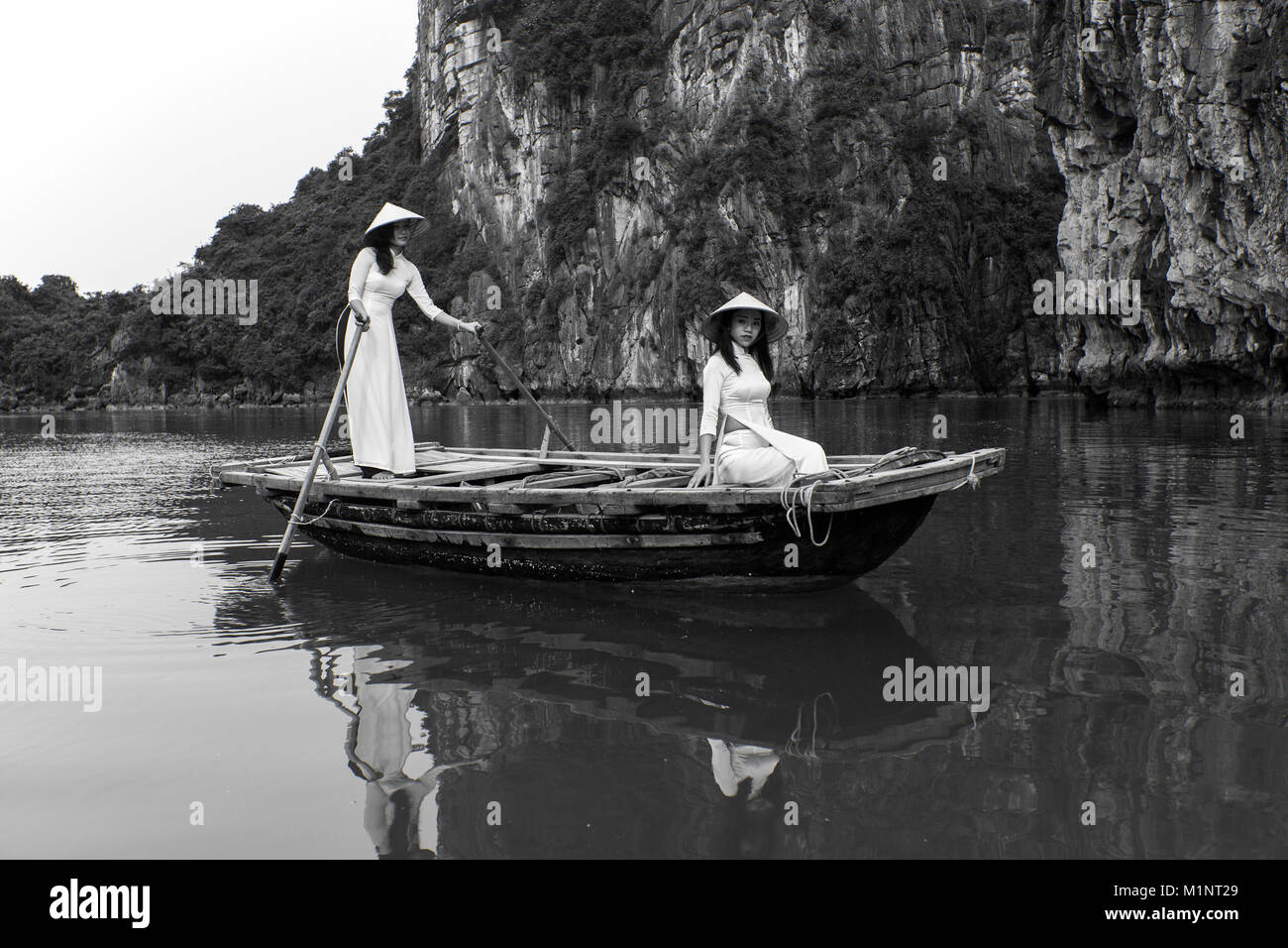 Giovani donne su un sampan (canotto) nella baia di Halong, Vietnam. Le isolette di calcare e di formazioni rocciose sono diventati un'UNESCO area protetta. Foto Stock
