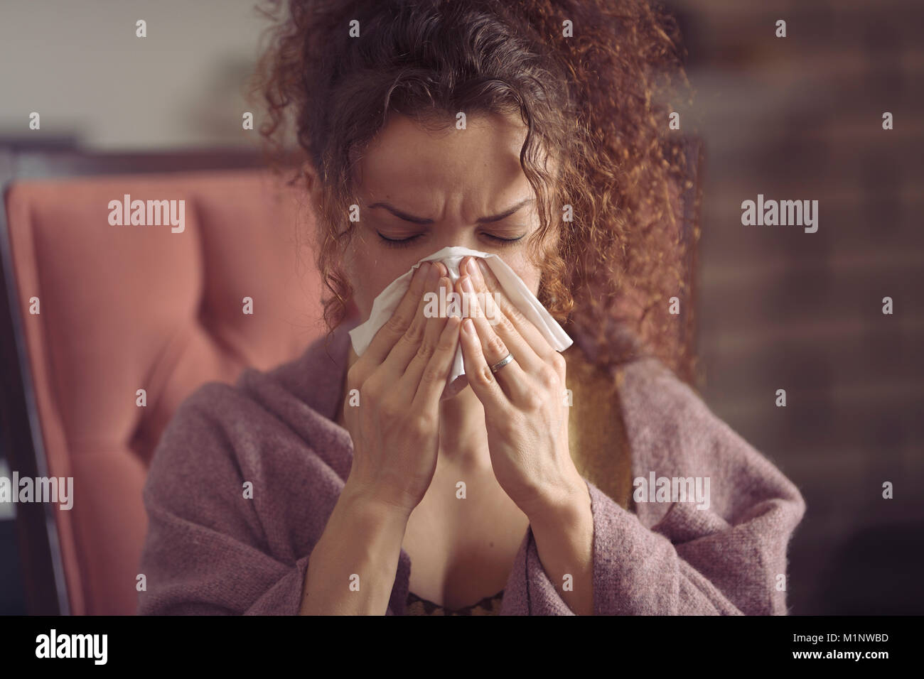 Donna soffiando il suo naso che cola o starnutire in un fazzoletto di carta Foto Stock