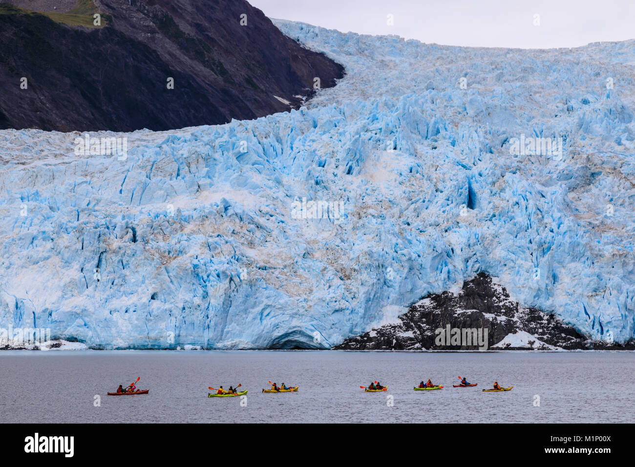 Kayaks colorati, Aialik Glacier, blu ghiaccio e montagne, Harding Icefield, il Parco nazionale di Kenai Fjords, vicino a Seward, Alaska, Stati Uniti d'America, America del Nord Foto Stock