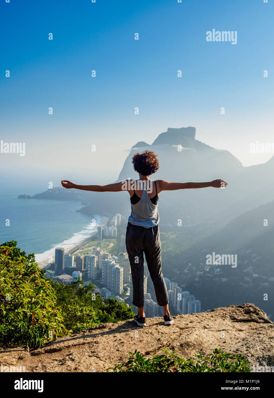 Ragazza brasiliana guardando verso la Pedra da Gavea e Sao Conrado da Dois Irmaos montagna, Rio de Janeiro, Brasile, Sud America Foto Stock