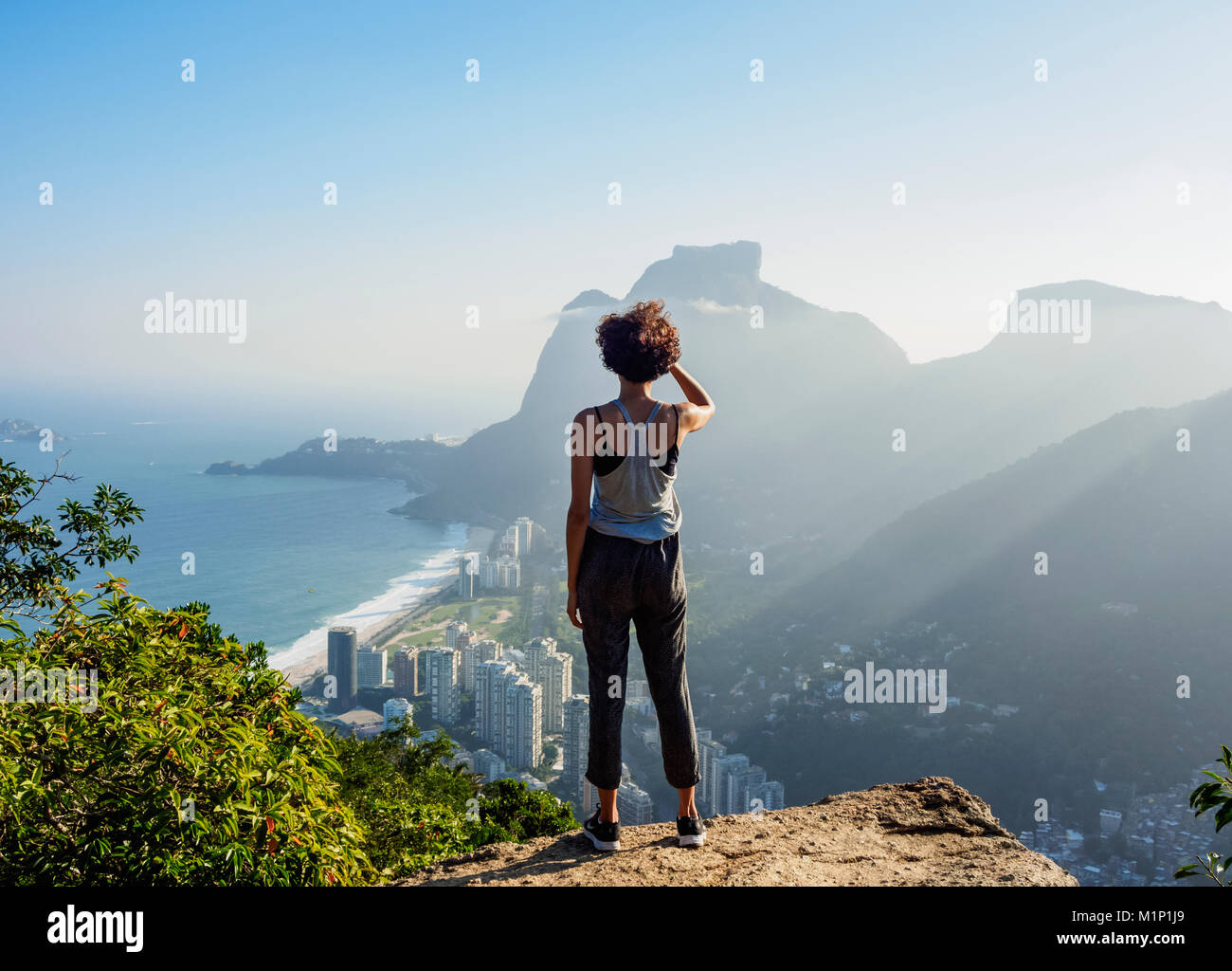 Ragazza brasiliana guardando verso la Pedra da Gavea e Sao Conrado da Dois Irmaos montagna, Rio de Janeiro, Brasile, Sud America Foto Stock
