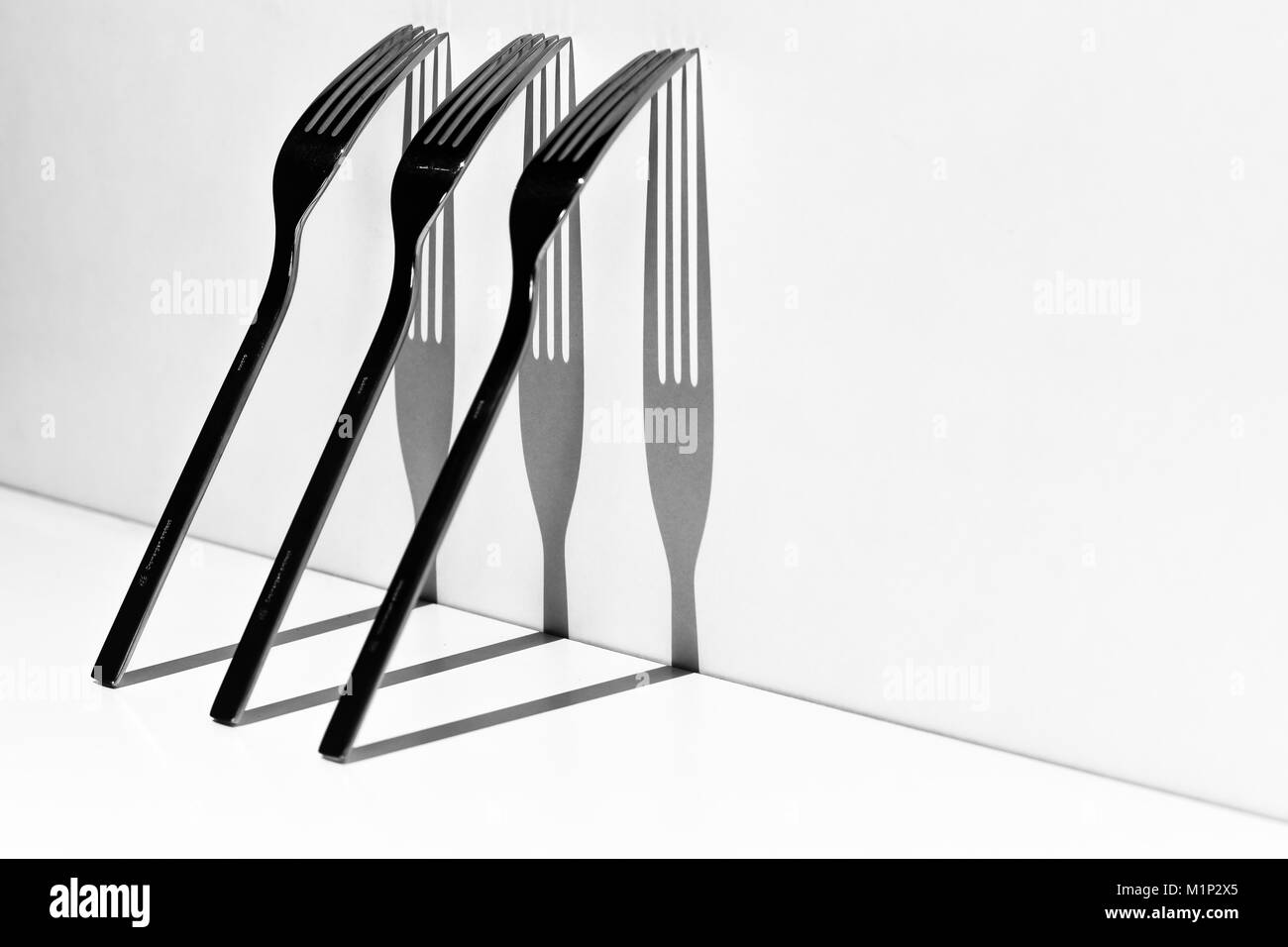 Forche appoggiarsi contro un muro bianco e getta un ombra Foto Stock