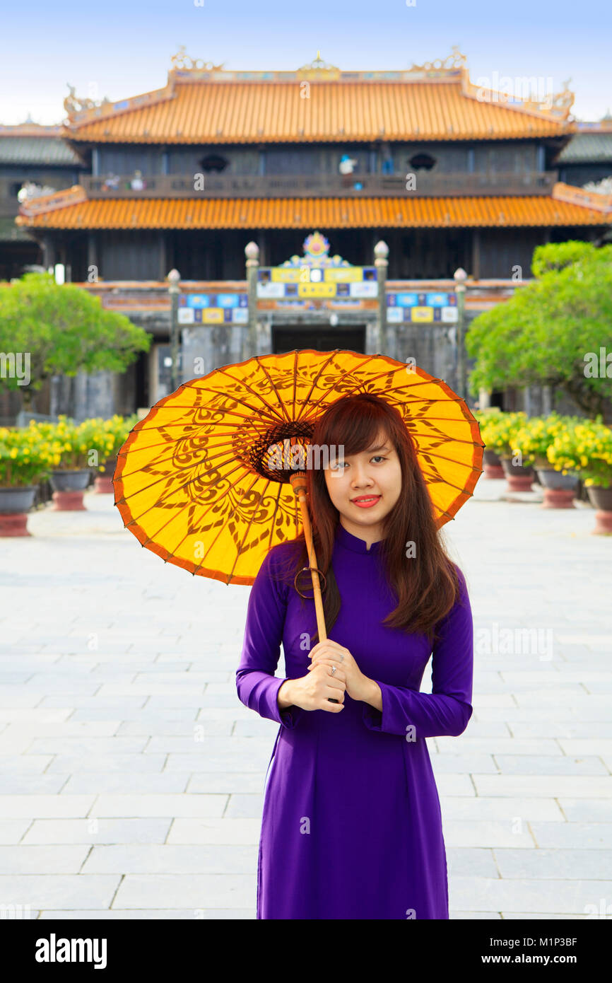 La donna in un tradizionale Ao Dai vestito con un ombrellino di carta nella Città Purpurea Proibita di tonalità, UNESCO, Thua Thien Huê, Vietnam, Indocina, Asia Foto Stock