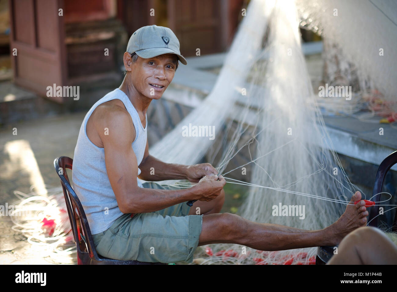 Pescatore vietnamita rammendo un net, Quang Nam, Vietnam, Indocina, Asia sud-orientale, Asia Foto Stock