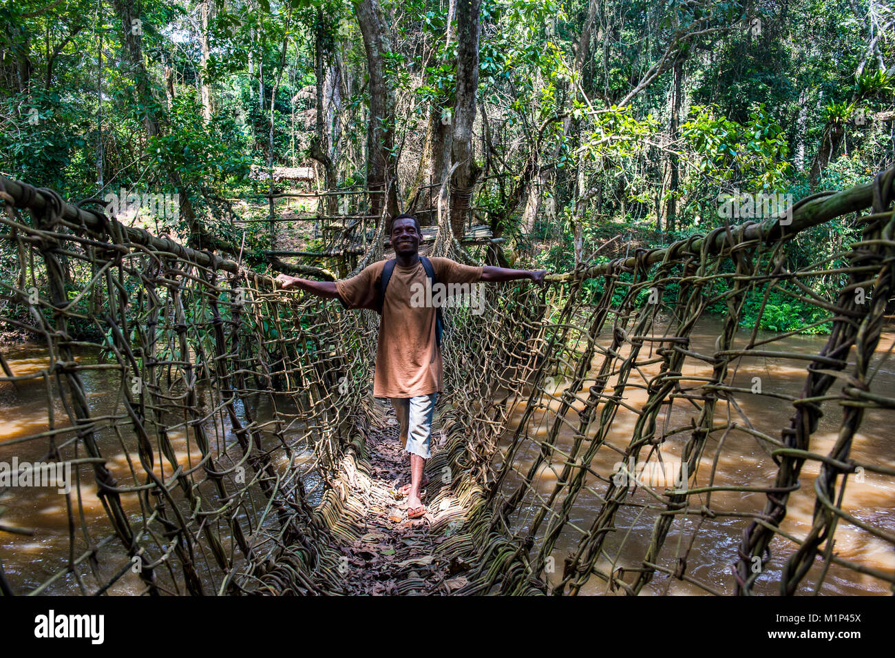 Pigmeo di camminare su un fatto a mano vine ponte in Dzanga-Sangha Park, sito Patrimonio Mondiale dell'UNESCO, Repubblica Centrafricana, Africa Foto Stock