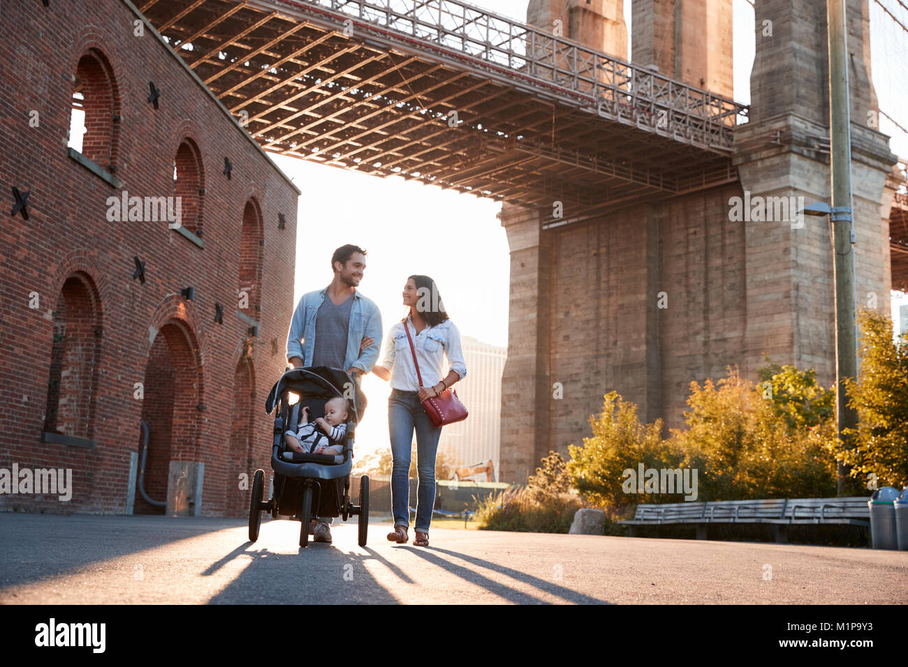 Famiglia giovane con una figlia prendendo a piedi su una strada Foto Stock