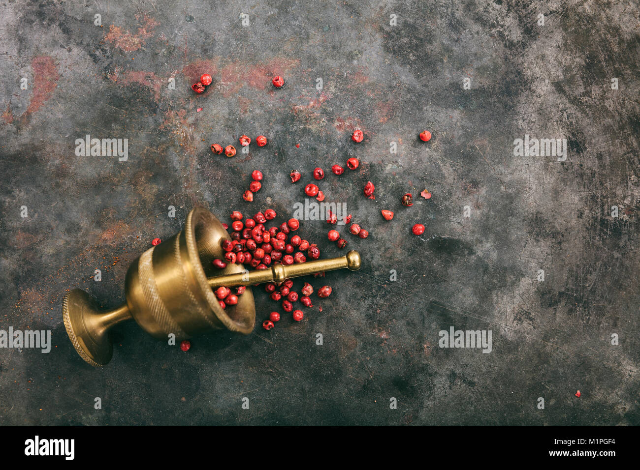 Pepe rosa semi e un mortaio di ottone su metallo arrugginito sfondo, vista dall'alto, spazio di copia Foto Stock