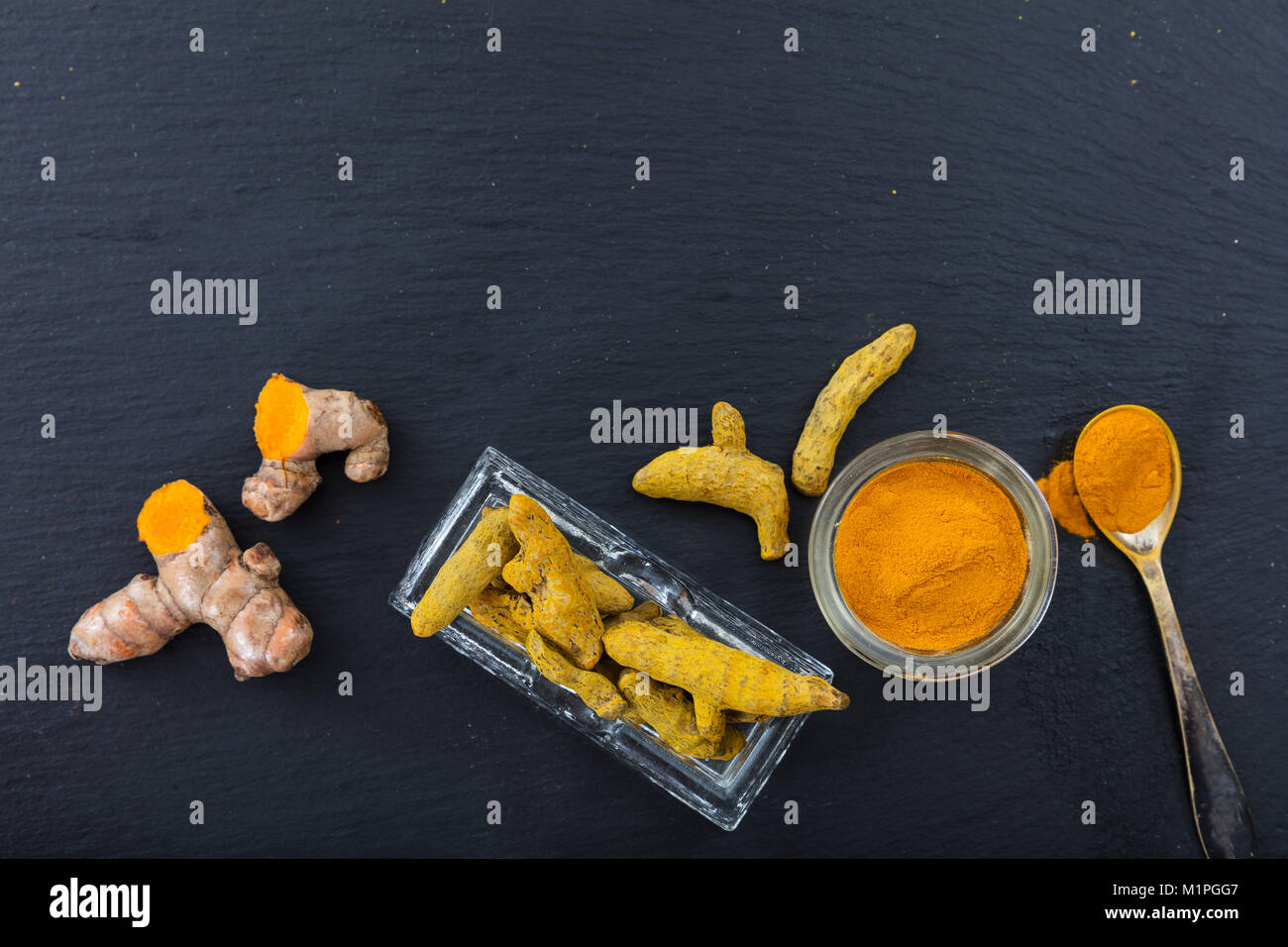 Freschi e Secchi o di curcuma curcumina radici e polvere su sfondo nero. Vista superiore, spazio di copia Foto Stock
