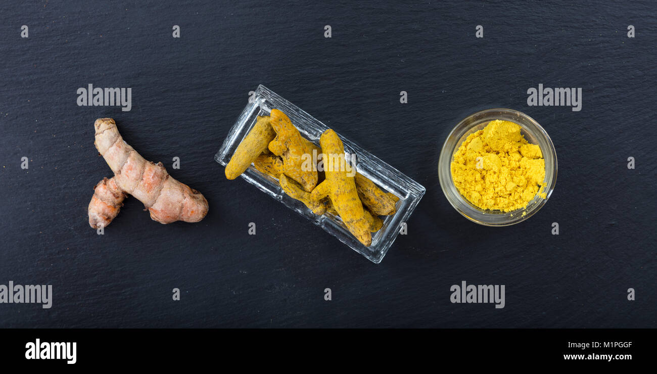 Freschi e Secchi o di curcuma curcumina radici e polvere su sfondo nero. Vista superiore Foto Stock