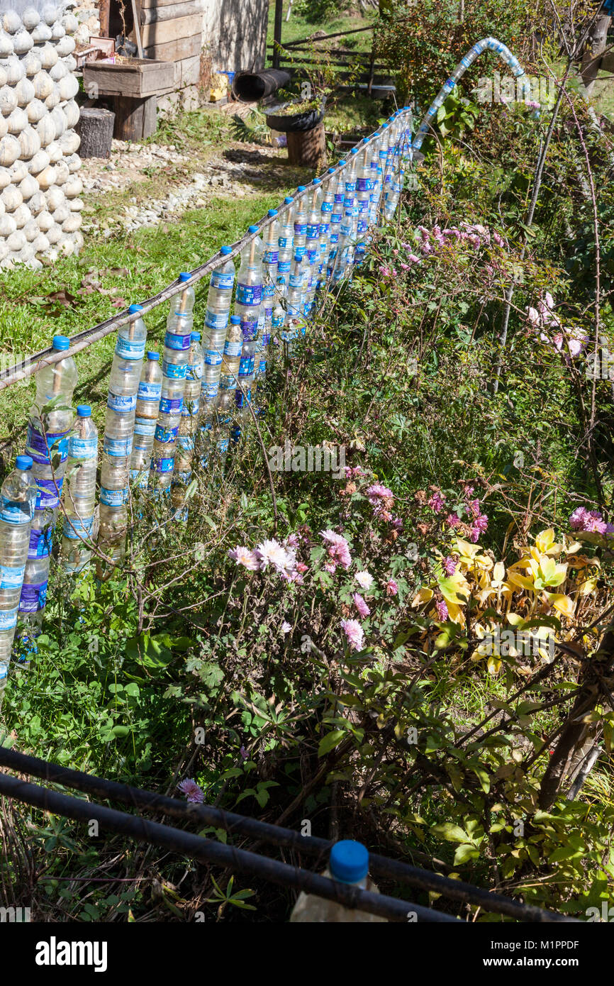 Bumthang, Bhutan. Il riciclaggio. Plastica bottiglie di acqua usata per formare una recinzione intorno al giardino di fiori. Foto Stock
