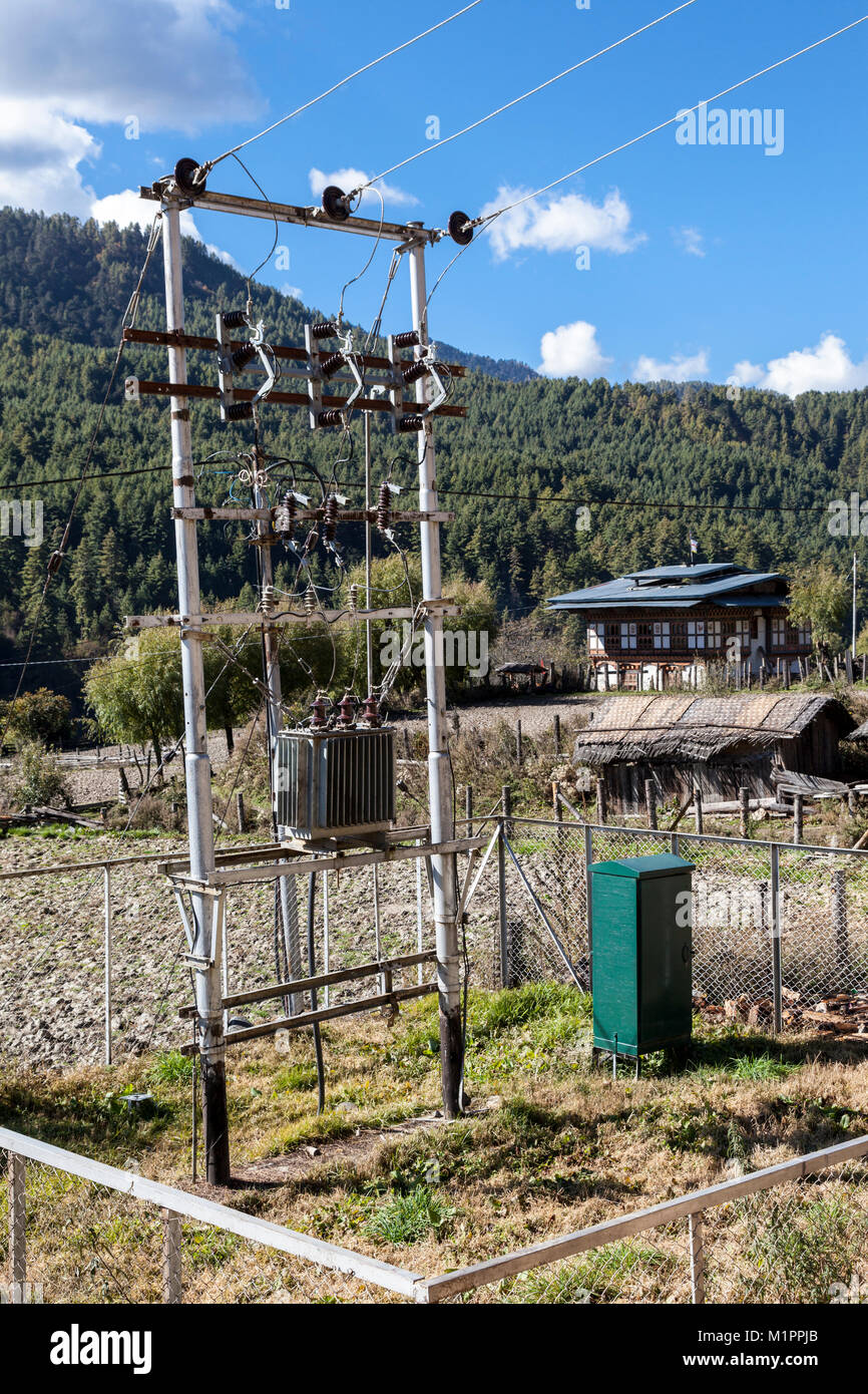 Bumthang, Bhutan. Trasformatore di energia elettrica in zona rurale vicino Prakhar, Chumey Valley. Middle-class house in background. Foto Stock