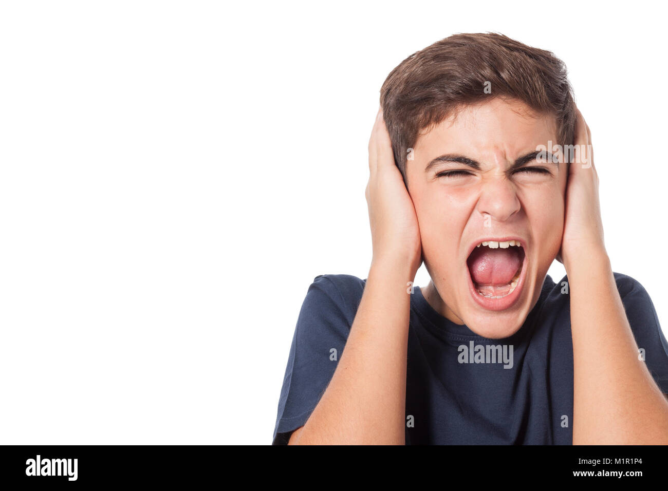 Frustated ragazzo gridando e coprendo i suoi orecchi Foto Stock