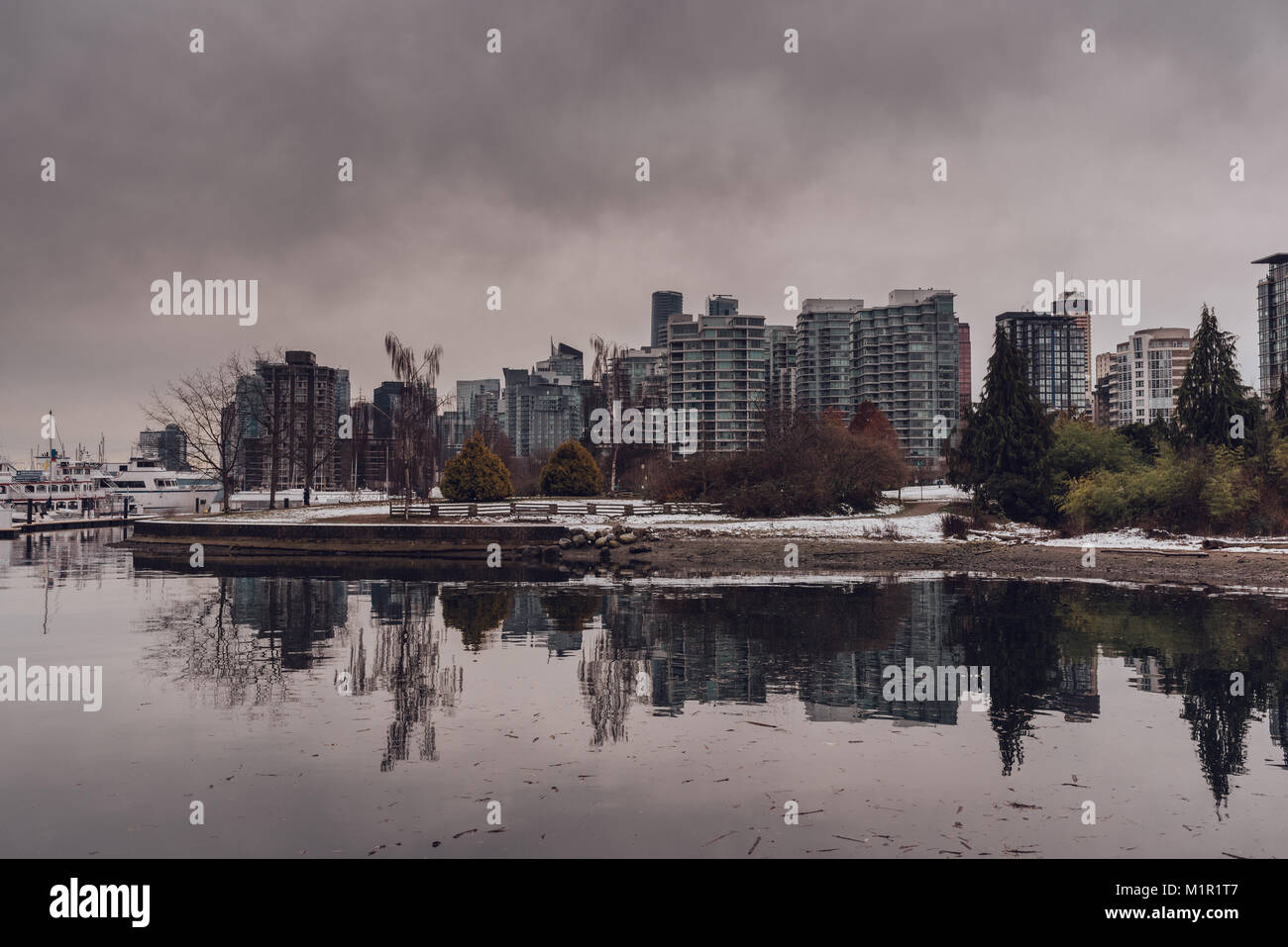 Vista del porto e della città di Vancouver (BC, Canada) grattacieli con riflessi nell'acqua in un nuvoloso giorno d'inverno. Foto Stock