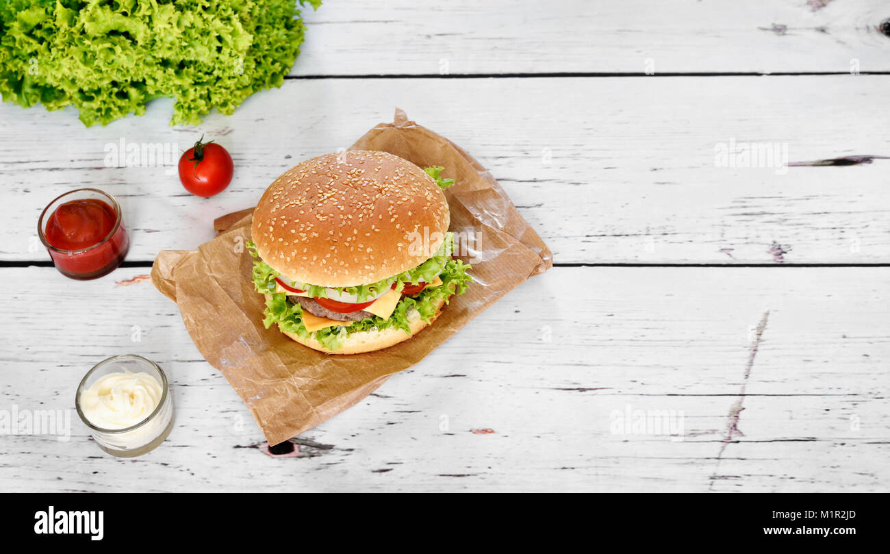 Burger Gourmet con salse su un tavolo bianco. Hamburger o cheeseburger con pomodori freschi, lattuga e polpetta di carne di manzo, fast food sfondo. Foto Stock