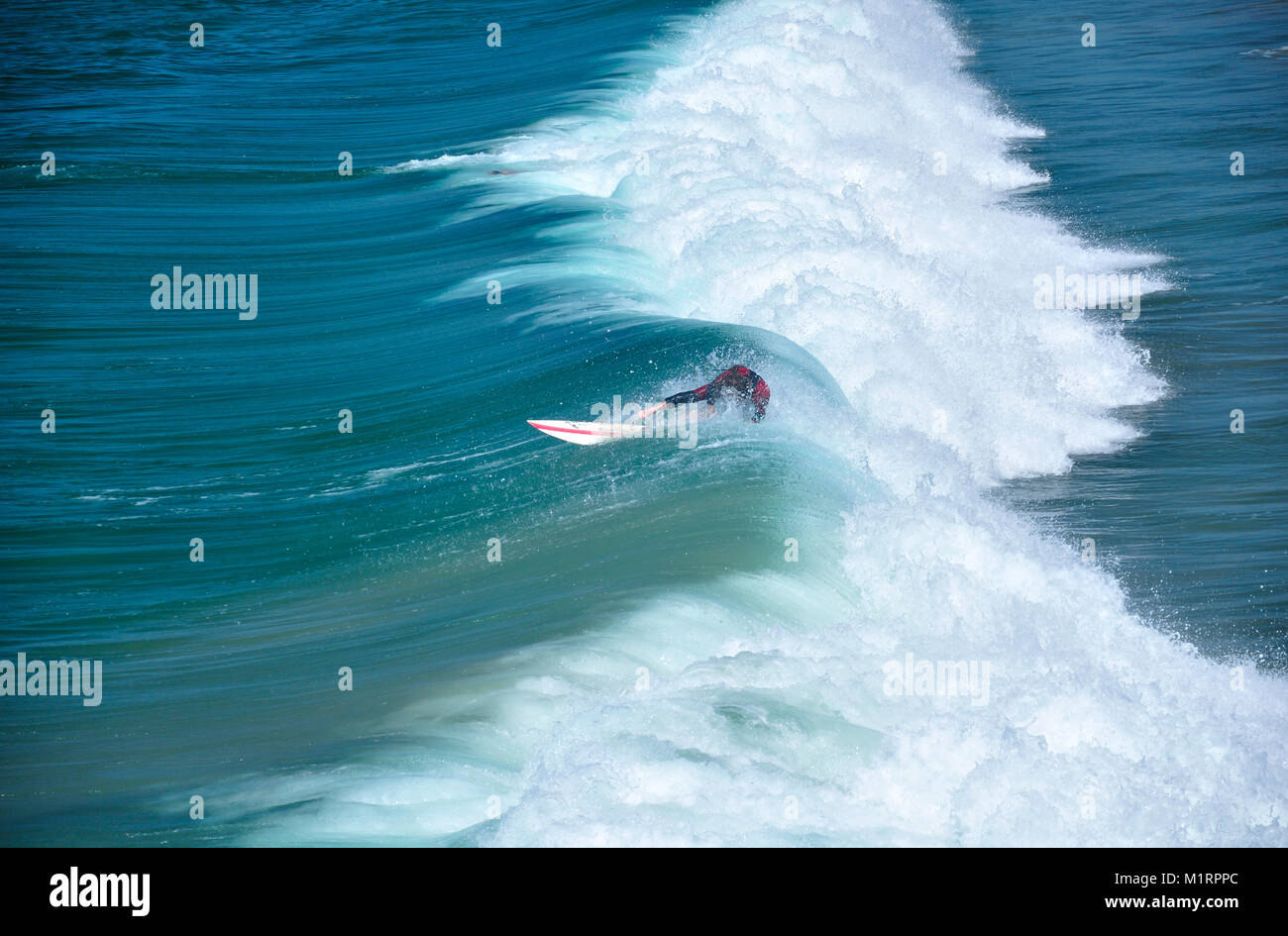 Un surfista cavalcare le onde e spazzare via a Manhattan Beach California in una giornata di sole sulla costa ovest. Foto Stock