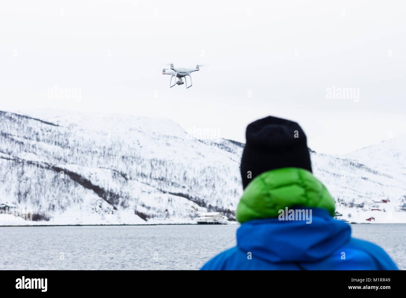 La Norvegia. Operatore drone guardando drone in volo sopra il fiordo norvegese. Foto Stock