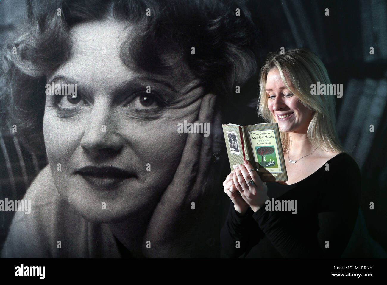 Programma pubblico e Coordinatore Eventi Ollie Quinn legge una copia del primo di Miss Jean Brodie da Scottish autore Muriel Spark accanto a un ritratto dello scrittore presso la Biblioteca Nazionale di Scozia a Edimburgo. Foto Stock