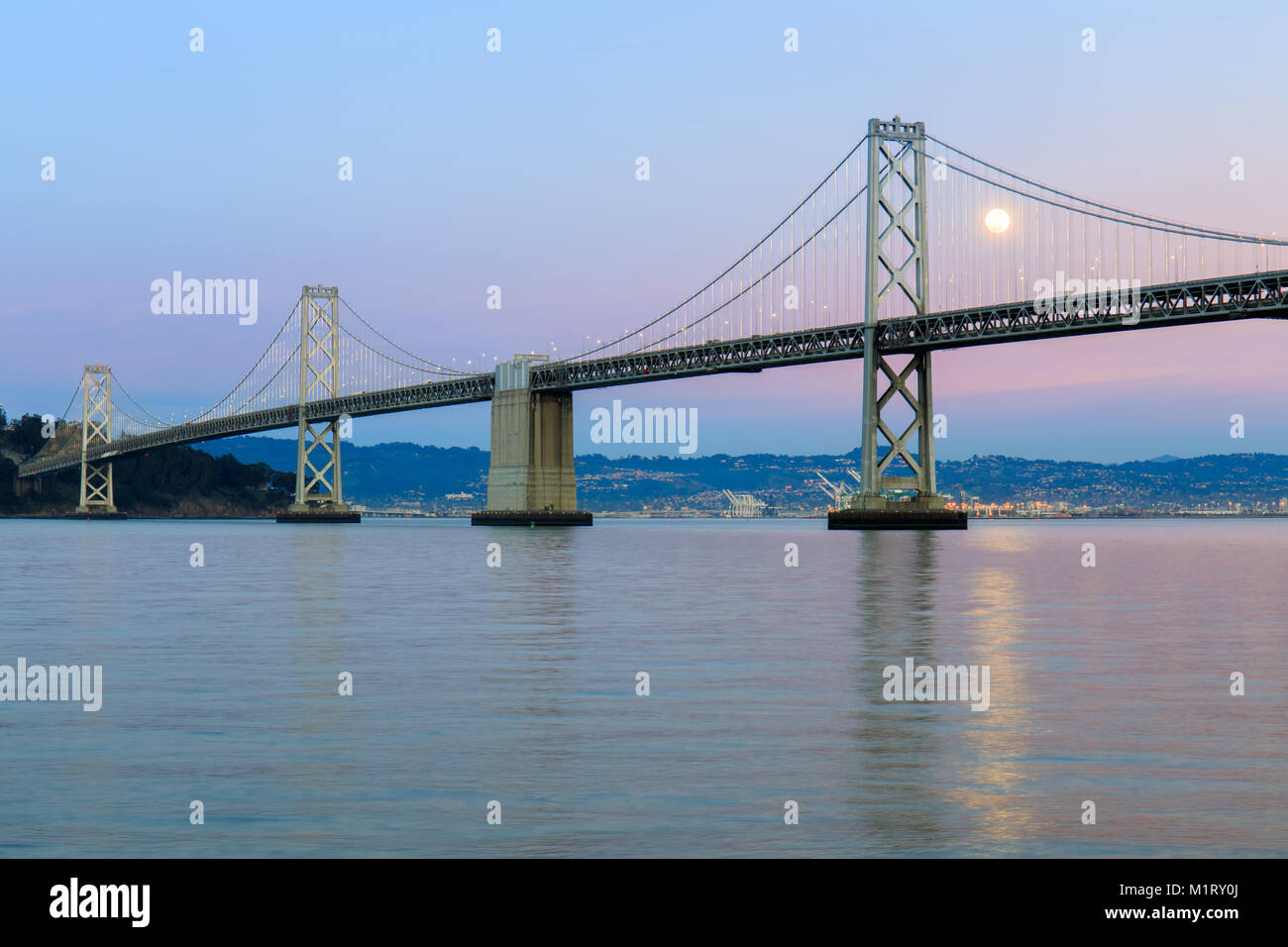 San Francisco-Oakland Bay Bridge con Full Moon Rising e rosa e blu Cielo di tramonto. Foto Stock