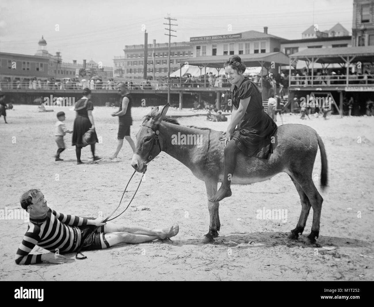 Donna seduta su Donkey mentre l uomo giace sulla sabbia Holding Redini, Atlantic City, New Jersey, Stati Uniti d'America, Detroit Publishing Company, 1901 Foto Stock
