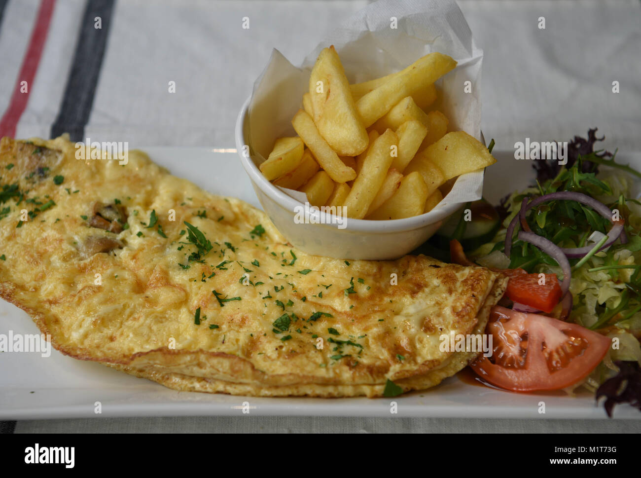 La colazione o il brunch di una casalinga frittata di uova servito e pronto da mangiare con il lato ordine di patatine o patate fritte Foto Stock