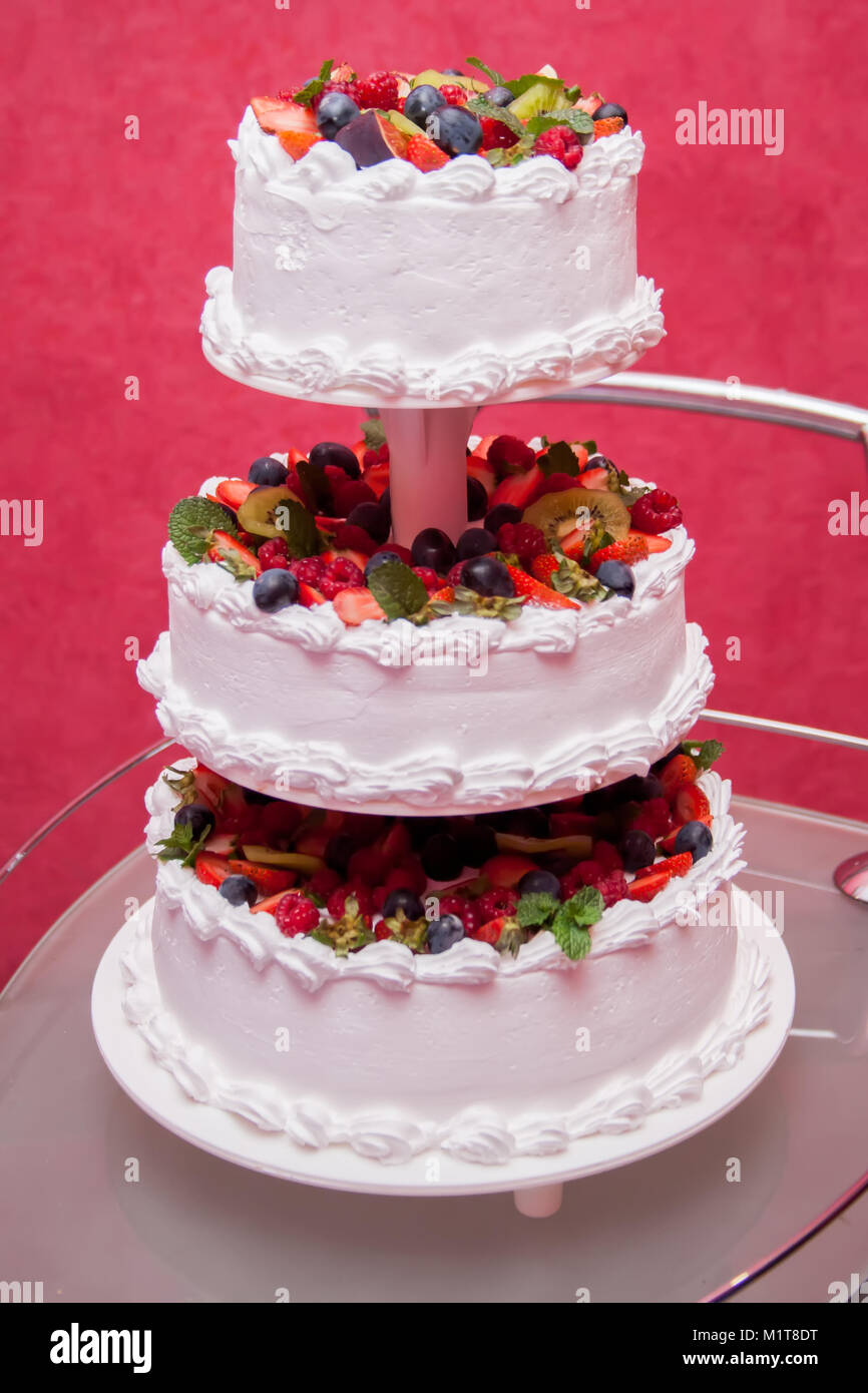 Torta nuziale decorata con fiori e frutti di bosco Foto Stock