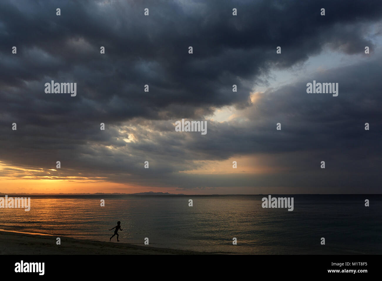 Giovane ragazzo in esecuzione su di una spiaggia di sabbia al tramonto colorato, Arcipelago Banyak, Sumatra, Indonesia, Asia sud-orientale, Asia Foto Stock