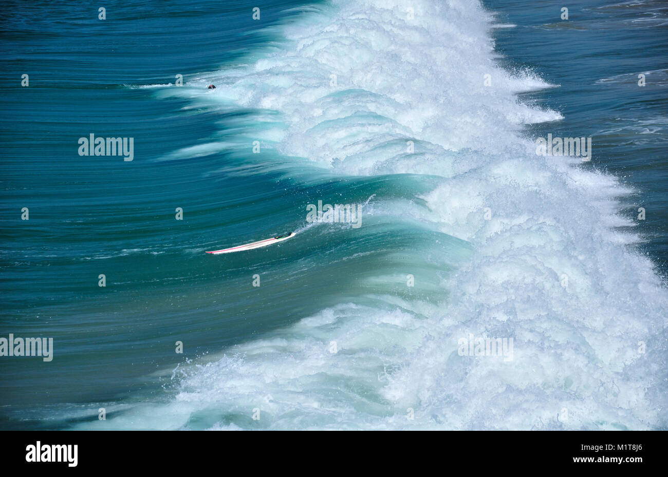 Un surfista tergitura nell'Oceano Pacifico delle onde che si infrangono sulla battigia verso il basso su Manhattan Beach California in una giornata di sole sulla costa ovest. Foto Stock