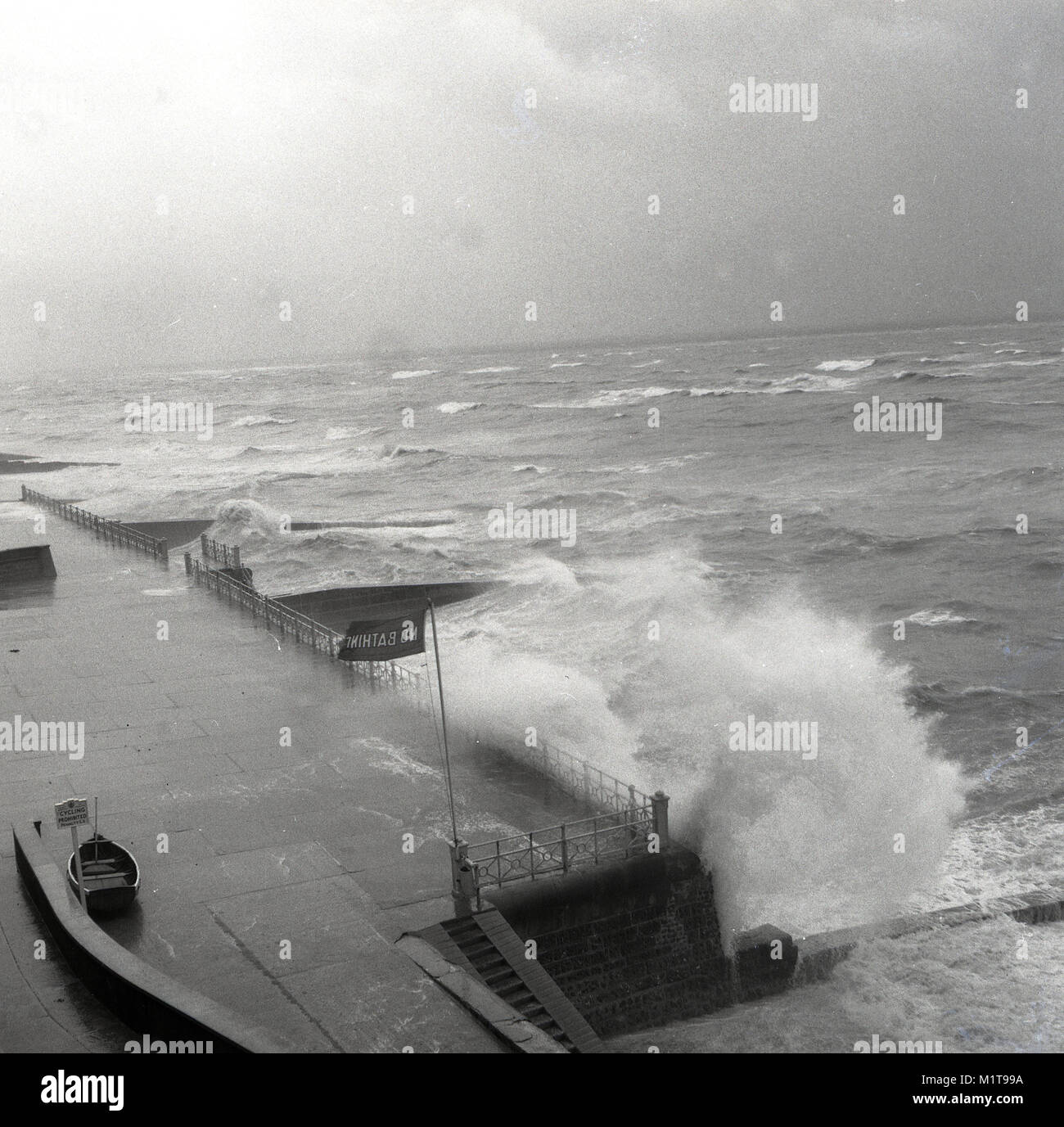 Degli anni Cinquanta, storico, Inghilterra, forti venti e tempeste producono grandi onde che crash oltre il concourse o lungomare a costa. Foto Stock