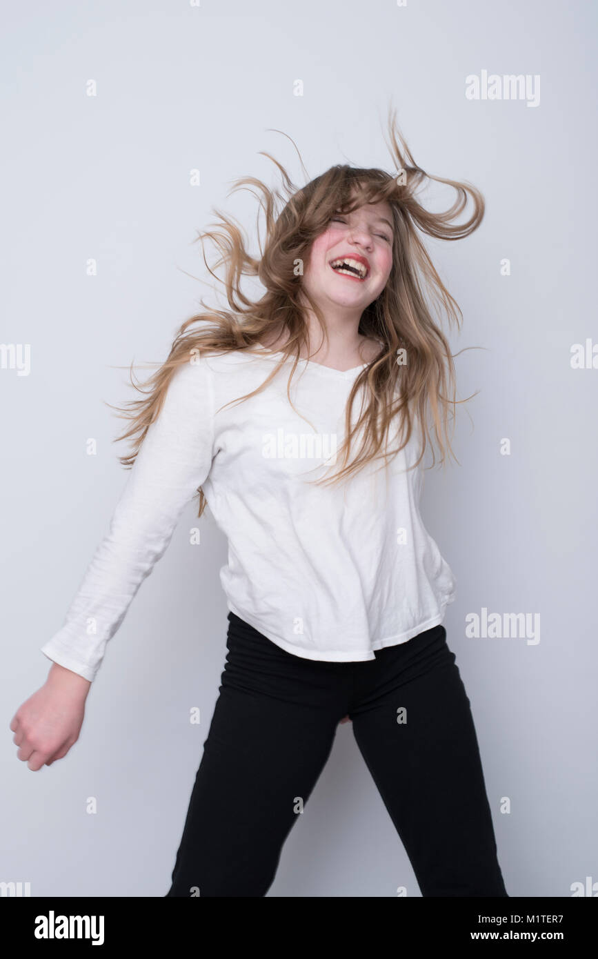 Sorridono felici ragazza danzante e indossa una camicia bianca e pantaloni neri su sfondo bianco, intenzionale sfocatura del movimento Foto Stock