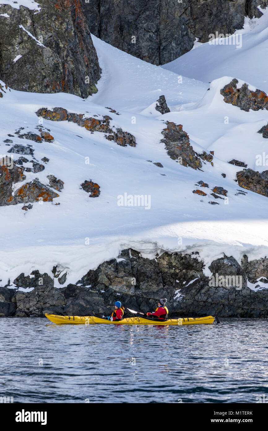 Kayakers esplorare coperta di neve Ronge isola; penisola Arctowski; Antartide Foto Stock