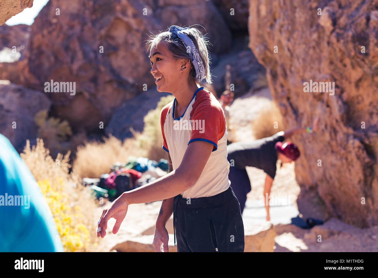 Petite donna asiatica arrampicata su roccia all'aperto risate mentre agli spettatori Foto Stock