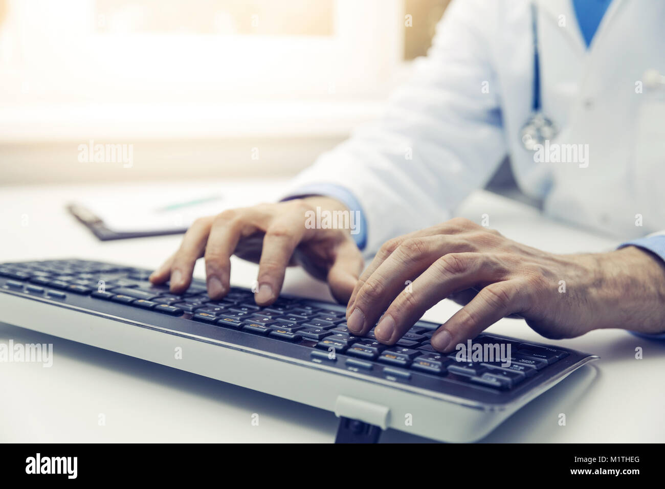 Medico digitando sulla tastiera del computer in ufficio. consultazione online Foto Stock