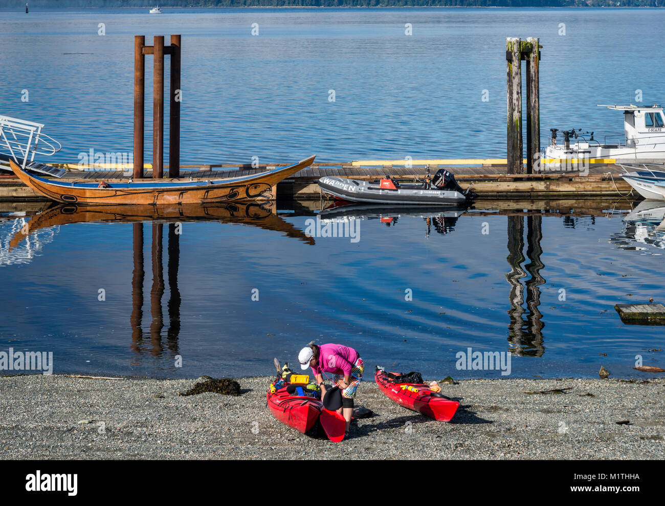 La donna la preparazione di kayak per un viaggio, Boat Harbour nel villaggio di Alert Bay sull'Isola di cormorani, North Vancouver Island area, British Columbia, Canada Foto Stock