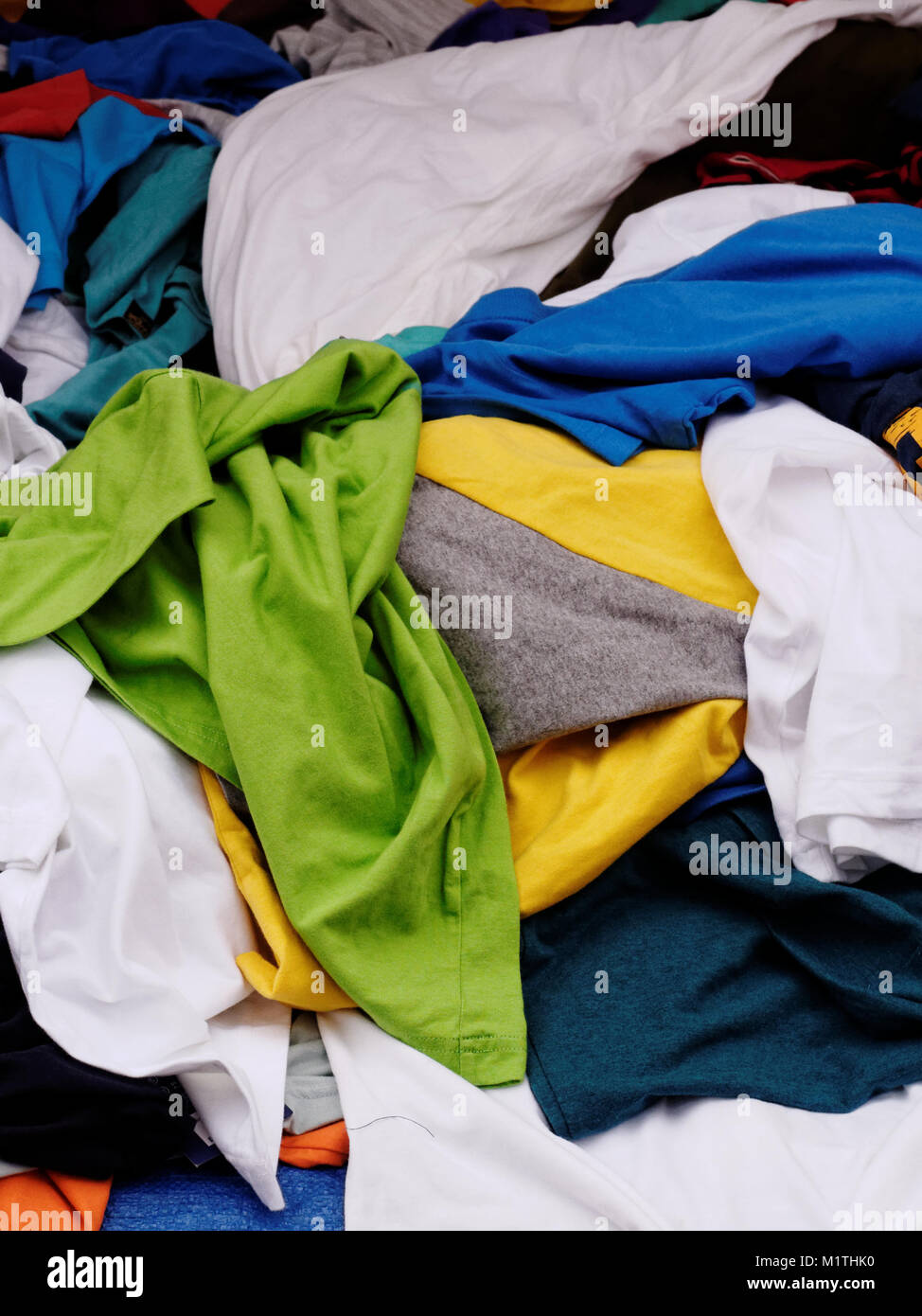 Multi-colore, verde, blu, giallo e bianco, mucchio di vestiti in vendita nel negozio di abbigliamento nel mercato di strada Foto Stock